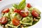 Close-up of Ravioli dish with fresh pesto sauce and cherry tomatoes, garnished with pine nuts and basil leaves