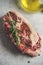 Close up of raw beef steak with rosemary and olive oil at grey concrete kitchen table. Butcher background with fresh beef meat.