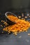 Close up of Raw Masur dal or masoor lentils or pink lentils in a black colored clay bowl on wooden surface.