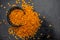 Close up of Raw Masur dal or masoor lentils or pink lentils in a black colored clay bowl on wooden surface.