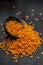 Close up of Raw Masur dal or masoor lentils or pink lentils in a black colored clay bowl on wooden surface