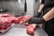 Close up of raw meat and woman butcher cutting meat with knife.