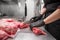 Close up of raw meat and woman butcher cutting meat with knife.