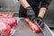 Close up of raw meat and woman butcher cutting meat with knife.