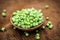 Close up of raw organic sprouted peas or beans or seed pod or Pisum sativum in a clay bowl on brown colored surface.