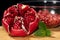 Close up of raw pomegranate opened on a wooden board with mnt and bawl of seeds