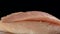 Close-up of a raw turkey fillet rotates on a black background. Fresh dietary poultry meat. Cooking fresh turkey. Turkey breast fil