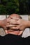 Close-up rear view of a male head with little hair or alopecia with his hands clasped at the nape of his neck