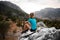 close-up rear view on woman resting on stone and enjoying beautiful mountains landscape.