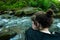 Close up Rear view of woman sitting by rushing water