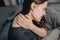 Close up rear view of young woman sitting bed at home scratching her shoulder and neck because of dry skin