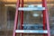 Close up. Red construction ladder. Blurred plastic drop cloth hangs from ceiling to floor in background