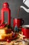 Close-up of red cups, jug serving chocolate, lemon sponge cake, lantern with candle and Christmas decorations, with selective focu