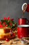 Close-up of red cups and saucepan serving chocolate, lemon sponge cake and Christmas decorations, with selective focus