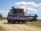 Close-up of a red harvester driving through a field for harvesting. Concept of agriculture