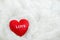 Close up of red heart with white love pattern on white furry background