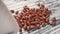 Close up of Red Kidney Beans sprinkled from a white ceramic cup on a wooden texture table.