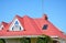 Close up on red metal roof with mansard, skylight window, roof guttering pipeline system