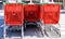 close up of red metallic and plastic trolleys tidied in several rows waiting for being used by buyers at a parking place in a