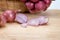 Close up red onion or shallots in wooden basket with sliced onion on wooden chopping block