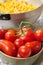 Close up of red tomatoes in a bowl and strainer full of pasta