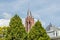 Close-up of the red tower of the Church of Saint John Sint-Janskerk among the tops of green leafy trees