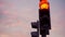 A close-up of a red traffic light turns green against a sunset sky.