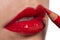 Close-up of red woman lips, applying lip pencil