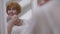 Close-up reflection of excited redhead senior bride touching face with flower in slow motion smiling. Happy Caucasian