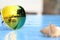 Close up reflex on lens of yellow sunglasses on blue wooden table can see shells, sun, sea view on it, concept summer on the beach
