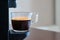 Close up of refreshing espresso pouring of capsule machine into a cup at home. Concept of coffee break