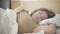 Close-up of relaxed chubby woman sleeping on white pillow in bed. Portrait of carefree young Caucasian lady resting in