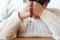 Close-up of religious senior person praying with red rosary. Focus on the hands