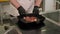 Close-up of a restaurant chef in gloves puts pork steak on a grill pan.