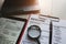 Close-up of resume with magnifying glass, computer laptop and pen on wooden background