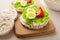 Close up rice cakes with cream cheese and quail eggs with lettuce and tomato on cutting board