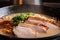 close-up of rich and creamy ramen broth with floating slices of roasted pork