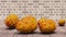 A close-up of a ripe orange horned melon fruits on the wooden table. Brick wall background