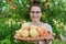 Close-up ripe plucked peaches in wicker plate in hands of woman farmer