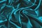 Close up of ripples in turquoise silk fabric. Satin textile background.