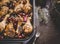 Close up of roasted chicken drumsticks with red onion and grapes on dark background