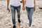 Close up of romantic couple hold hands and walk on sand