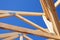 Close-up of rooftop beams connection against blue sky. Constructing wooden roof frame. Roofing construction