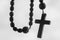 Close up rosary beads against white background. Selactive focus on cross. Christianity, religion, faith concept