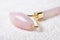 Close-up of rose quartz jade roller on towel. Anti age, lifting and toning treatment at home