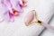 Close-up of Rose Quartz jade roller on towel on stone background. Anti age, lifting and toning treatment