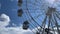 Close up of rotating ferris wheel on background of cloudy sky. Entertainment attraction with overview of city in