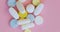 Close-up, rotation - blue, white and yellow pills on pink background.