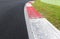 Close up of rough curb at right turn on motorsport track with green field and black asphalt