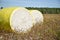 Close-up round bale of harvested cotton wrapped in yellow plastic.